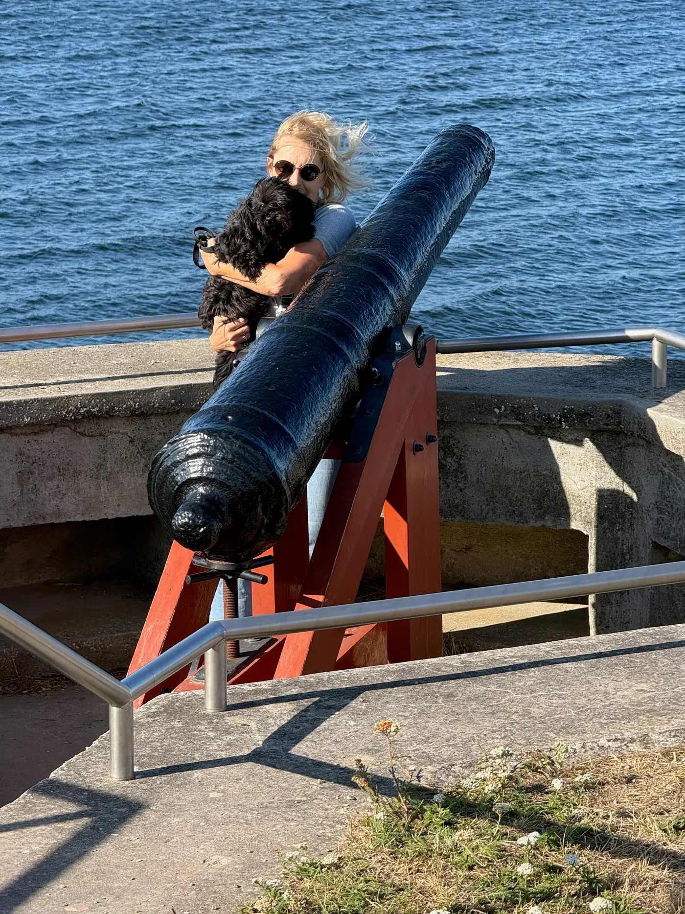 Malu auf dem Arm hinter einer alten schwarzen Kanone an der Festungsanlage von Veere, dahinter das Wasser — Donnerstag, 20. August 2026